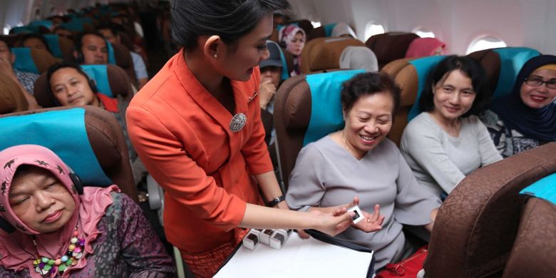 Pramugari Garuda Indonesia membagikan cokelat di tengah Kartini Flight rute Jakarta-Padang, Jumat (21/4/2017).