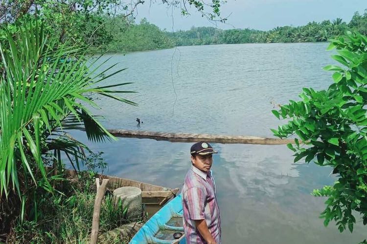 Samsul Bahrun berada di tepi sungai tempat hidup ratusan buaya yang berdampingan dengan ratusan warga