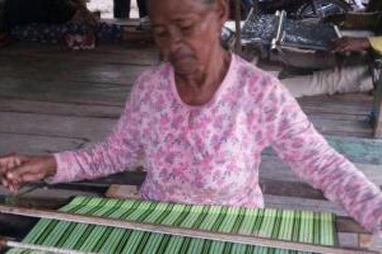 Wa Bantaha (60), warga Desa Worikana, Kecamatan Mawasangka Tengah, Kabupaten Buton Tengah, Sulawesi Tenggara sedang menenun sarung buton di bawah rumah panggung.