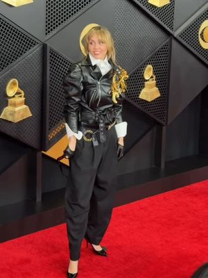 Miley Cyrus mencuri perhatian di Grammy 2026 lewat gaya rock chic serba hitam. Brooch raksasa berinisial namanya jadi statement.
