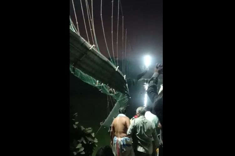 Tangkapan layar dari video yang merekam jembatan gantuh yang runtuh di Sungai Machhu di Kota Morbi, Negara Bagian Gujarat, pada Minggu (30/10/2022).