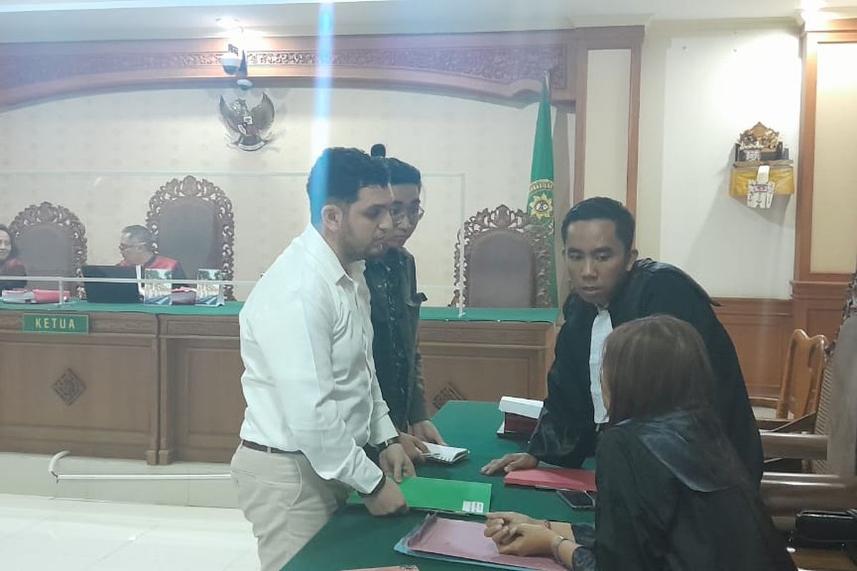 Mohammad Nizar Zghaib (32), pria warga negera Suriah saat berkonsultasi dengan penasehat hukumnya usai dituntut 3 tahun penjara terkait kasus suap penerbitan KTP WNI di Pengadilan Tipikor Denpasar pada Kamis (20/7/2023) malam. Kompas.com/ Yohanes Valdi Seriang Ginta