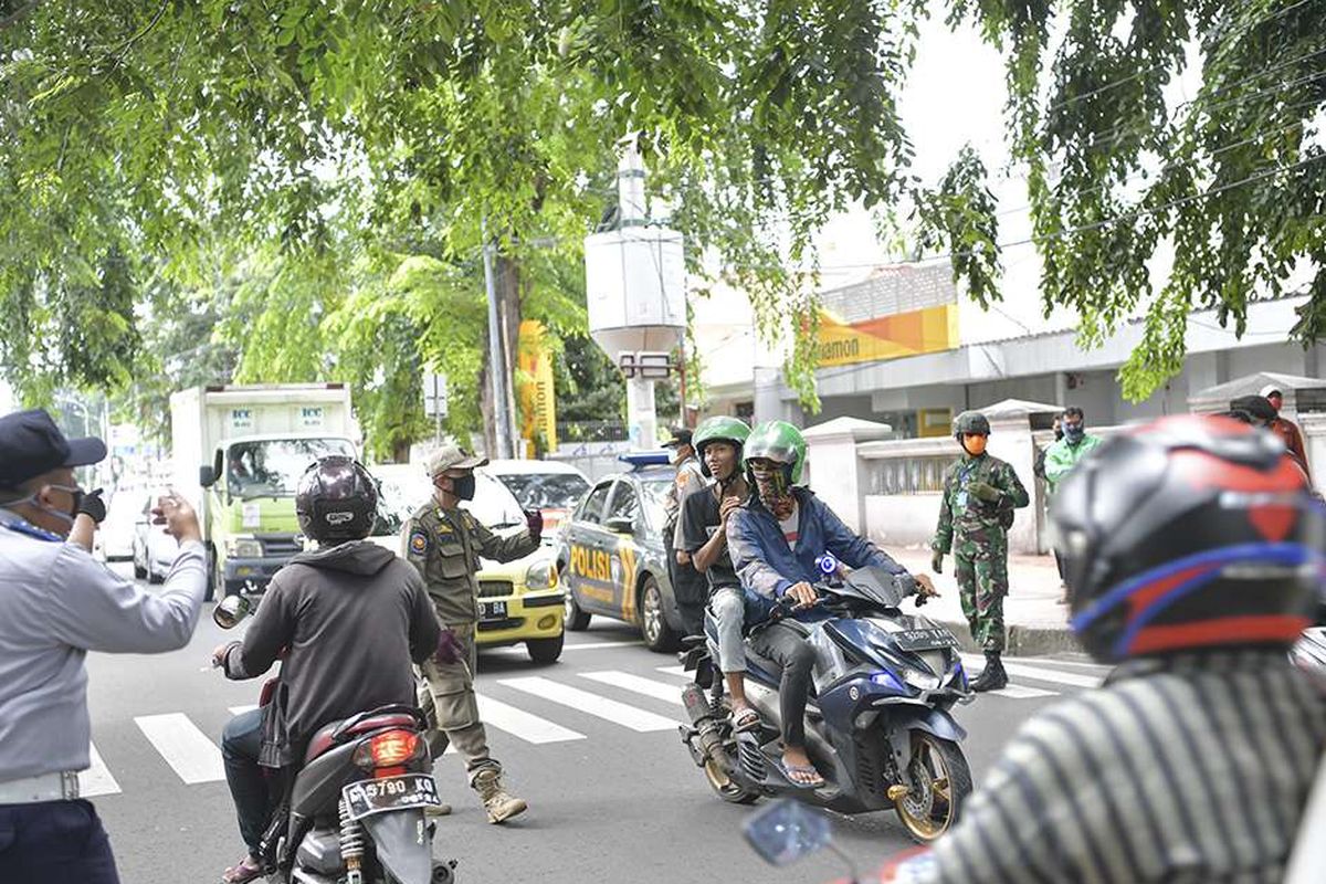 Petugas gabungan dari TNI, Polri, Polisi Pamong Praja DKI Jakarta dan Dsihub melakukan imbauan kepada pengendara motor untuk dapat mematuhi penerapan Pembatasan Sosial Berskala Besar (PSBB) di jalan cempaka putih raya, Cempaka Putih, Jakarta (11/4/2020). Iimbauan ini dilakukan agar masyarakat menerapkan pembatasan sosial berskala besar (PSBB) selama 14 hari, yang salah satu aturannya adalah pembatasan penumpang kendaraan serta anjuran untuk menggunakan masker jika berkendara.