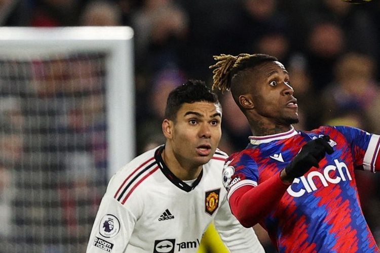 Gelandang Manchester United Casemiro (kiri) menatap bola saat penyerang Crystal Palace Wilfried Zaha menyundulnya pada Liga Inggris antara Crystal Palace vs Man United di Selhurst Park di London pada Rabu 18 Januari atau Kamis 19 Januari 2023 dini hari WIB. Dalam pertandingan itu, Casemiro santai menanggapi selfie seorang fan yang menerobos masuk lapangan.