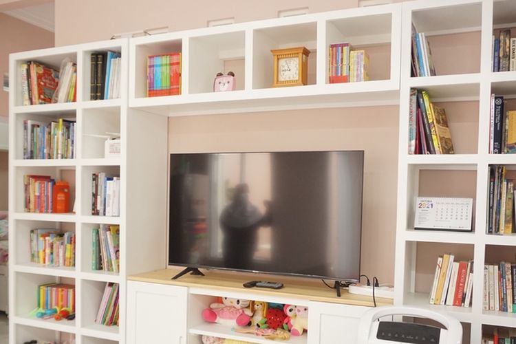 Ilustrasi TV dikelilingi rak buku di ruang tamu. 