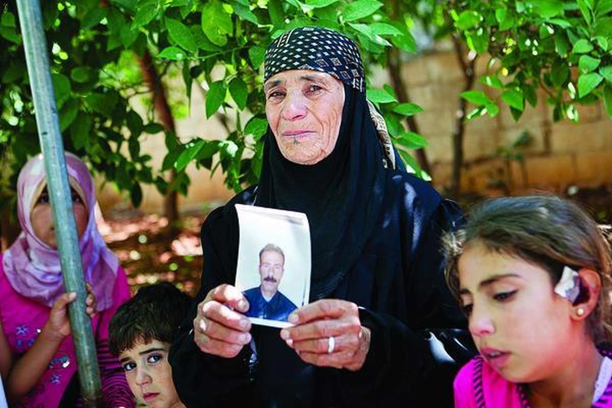 Suthani,  ibu di Desa Kfar Sijna, Suriah utara, menunjukkan foto anak laki-lakinya, Khalil (37), Selasa (10/7). Khalil bersama dua anaknya yang masih berusia satu dan dua tahun tewas saat sebuah peluru meriam yang ditembakkan tentara Pemerintah Suriah meledak di dekat rumahnya, Senin (9/7).  