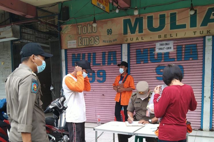Petugas tengah mendata masyarakat yang mengabaikan protokol kesehatan di Pasar Jaya Elang, Pademangan, Jakarta Utara, Jumat (18/2/2022).