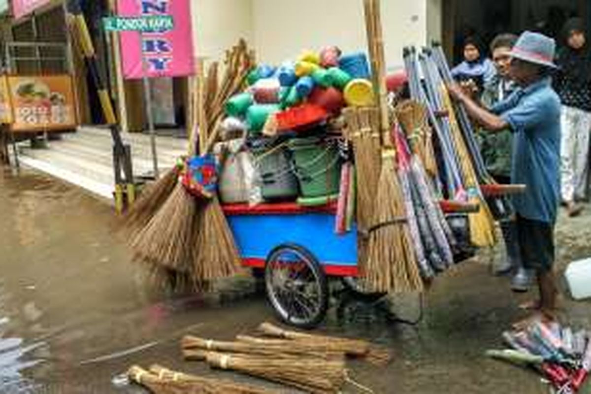 Astija (60) tengah membereskan barang dagangannya setelah sempat terbawa aliran air banjir di Jalan Pondok Karya, Kelurahan Pela Mampang, Mampang Prapatan, Jakarta Selatan, Kamis (21/4/2016).