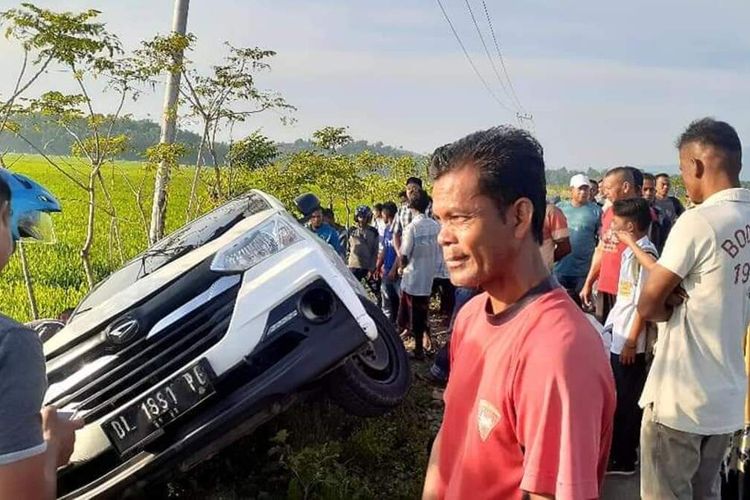 warga berkerumun melihat mobil yang digunakan untuk mencuri ternak sapi terperosok ke parit.