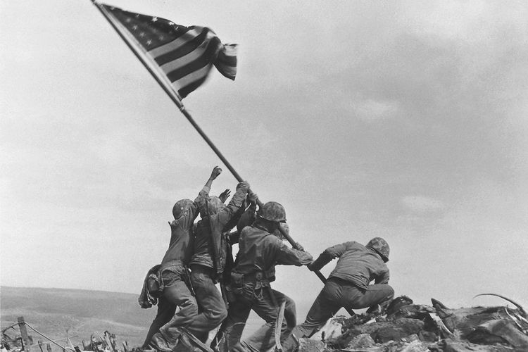 Pertempuran Iwo Jima. Marinir AS mengibarkan bendera Amerika di atas Gunung Suribachi, Iwo Jima, pada 23 Februari 1945.
