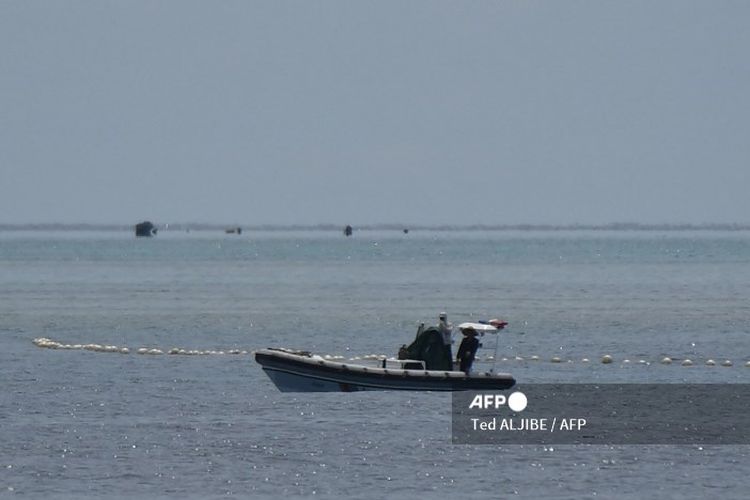 Foto yang diambil pada 22 September 2023 ini menunjukkan personel pasukan penjaga pantai China berada di atas perahu karet lambung kaku mereka di samping penghalang terapung saat mereka menjaga jalur menuju Scarborough Shoal yang dikuasai China di perairan Laut China Selatan yang disengketakan. Tiongkok, yang mengklaim kedaulatan atas hampir seluruh Laut Cina Selatan, merebut kendali atas Scarborough Shoal dari Filipina pada tahun 2012. Sejak saat itu, China telah mengerahkan kapal penjaga pantai dan kapal-kapal lain untuk memblokir atau membatasi akses ke daerah penangkapan ikan yang telah dimanfaatkan oleh beberapa generasi warga Filipina. 