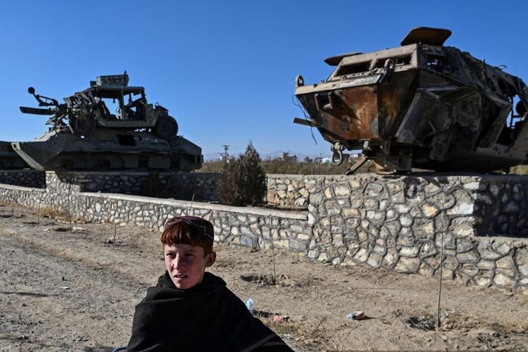 Dalam gambar yang diambil pada 13 November 2021, seorang pemuda mengendarai sepeda melewati kendaraan lapis baja yang hancur yang dipajang di sepanjang jalan di Ghazni.