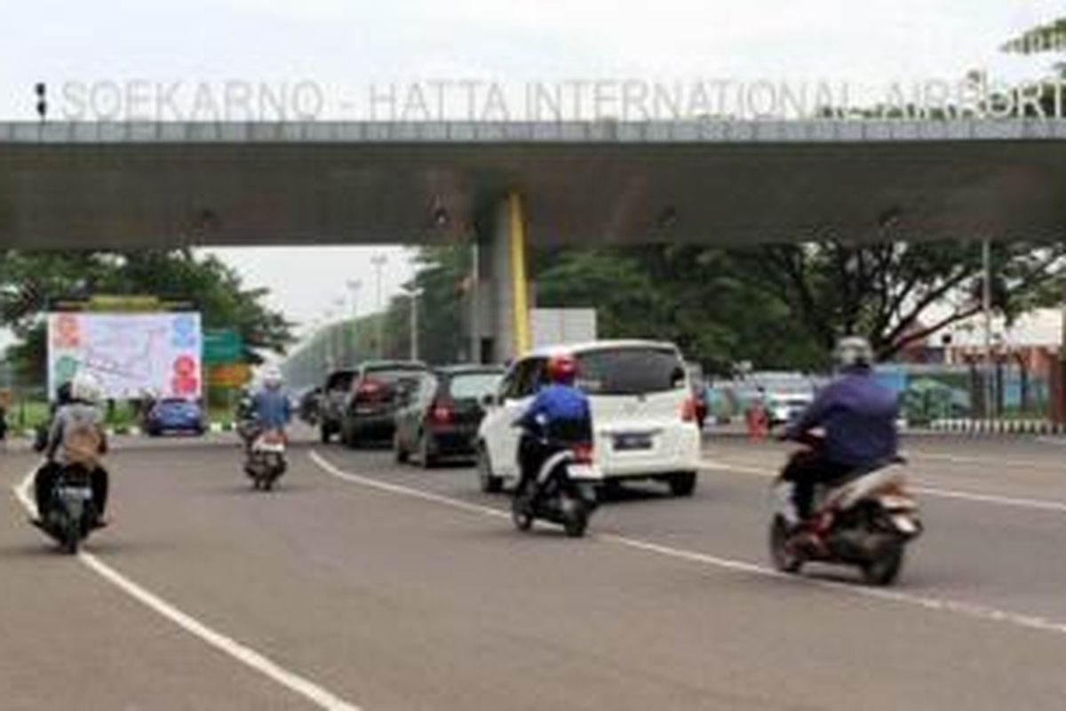 Kendaraan melintas di dekat baliho yang berisi pengumuman rencana penutupan pintu M-1 Bandara Soekarno-Hatta, di pintu masuk M-1, Neglasari, Kota Tangerang, Kamis (19/12/2013). Rencananya, mulai 26 Desember ini, pintu M-1 (dari arah Kota Tangerang) akan ditutup dan arus lalu lintas akan dialihkan melalui jalan alternatif lainnya menuju bandara, ini terjadi terkait akan dibangunnya rel kereta api Bandara Soekarno Hatta yang akan melalui pintu belakang atau biasa dikenal dengan nama pintu M-1.