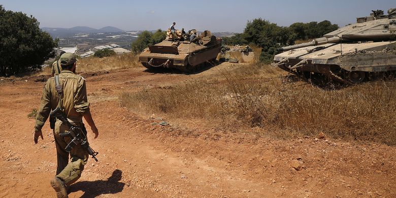 Tentara Israel berjalan dengan tank Merkava dan kendaraan angkut personel Namer dekat kota Avivim, di utara Israel berbatasan dengan Lebanon pada 23 Juli 2020.