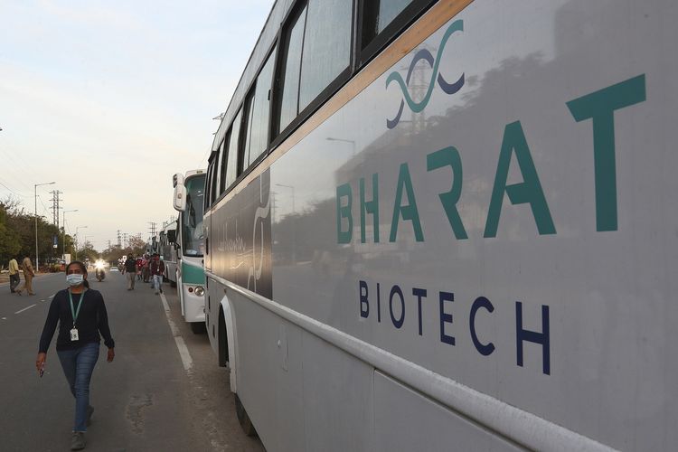 Seorang pegawai Bharat Biotech berjalan di samping bus milik perusahaan tersebut, yang diparkir di luar kantornya di pinggiran Hyderabad, India, pada 9 Januari 2021.