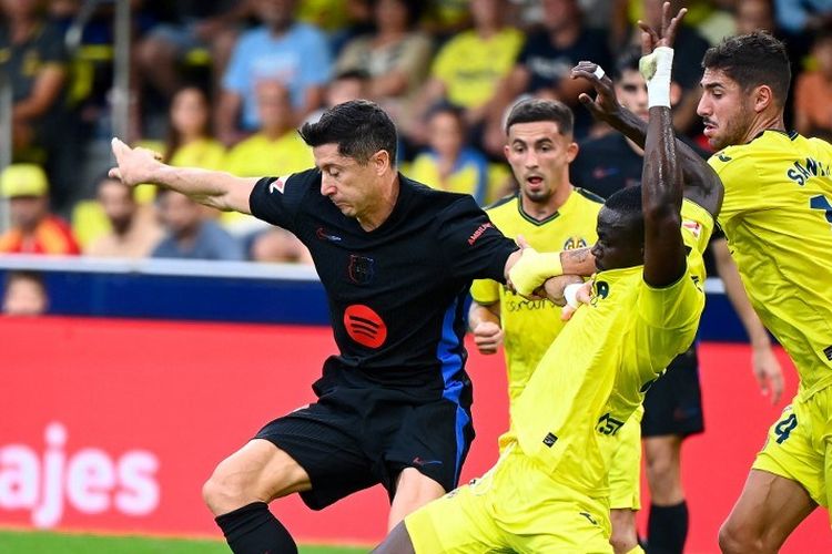Penyerang Barcelona Robert Lewandowski (hitam) berebut bola dengan bek Villareal Logan Costa selama pertandingan Liga Spanyol antara Villarreal vs Barcelona di Stadion La Ceramica di Vilarreal pada 22 September 2024. (Foto oleh JOSE JORDAN / AFP)