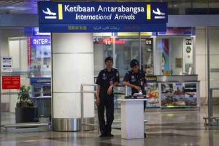 Polisi berjaga di terminal kedatangan di Bandara Internasional Kuala Lumpur, di Sepang, Malaysia, Jumat (18/7/2014). Malaysia Airlines mengatakan bahwa penerbangan MH17 kehilangan kontak di Ukraina. Pesawat terbang dari Amsterdam menuju Kuala Lumpur.