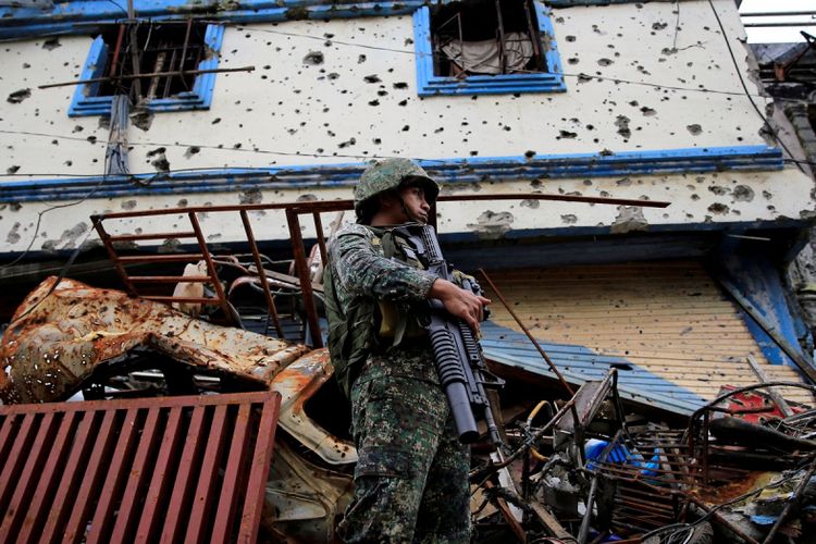 Seorang tentara pemerintah berjaga di depan bangunan dan rumah rusak saat pasukan melanjutkan penyerangan mereka pada hari ke-105 operasi pembersihan terhadap pro militan Islamic State yang mengontrol sebagian besar kota Marawi, Filipina, Senin (4/9). 