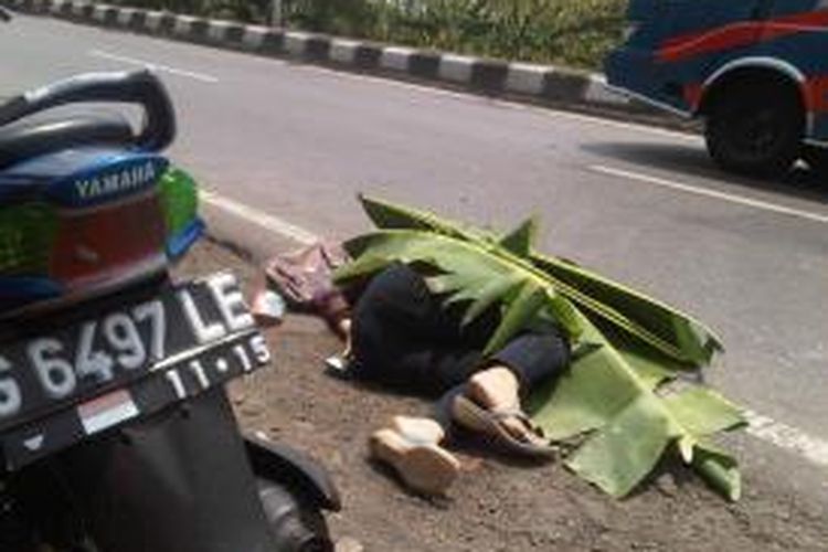 Jasad Setia Dwi Yuliani (20) warga Jalan Timor Timur, Kelurahan Panggung, Kota Tegal yang tewas terlindas truk di jalur pantura, Tegal, sempat ditutupi dengan daun pisang sebelum dipindahkan, Minggu (10/11/2013).
