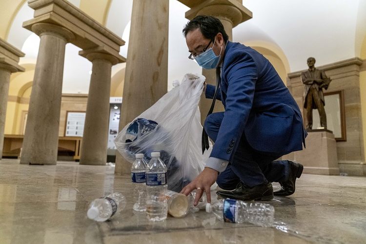 Andy Kim, anggota DPR dari Demokrat New Jersey membersihkan puing-puing dan sampah yang berserakan di lantai pada dini hari Kamis, 7 Januari 2021, setelah demonstran menyerbu Capitol di Washington, Rabu.