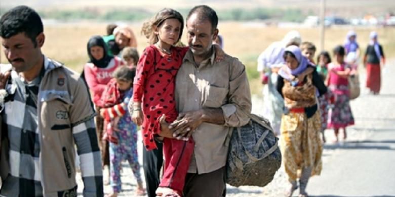 Seorang pengungsi Yazidi Irak mengendong putrinya saat melintasi perbatasan Suriah, Senin (11/8/2014). Sekitar 20.000 warga minoritas Yazidi masih terjebak di Gunung Sinjar. 
