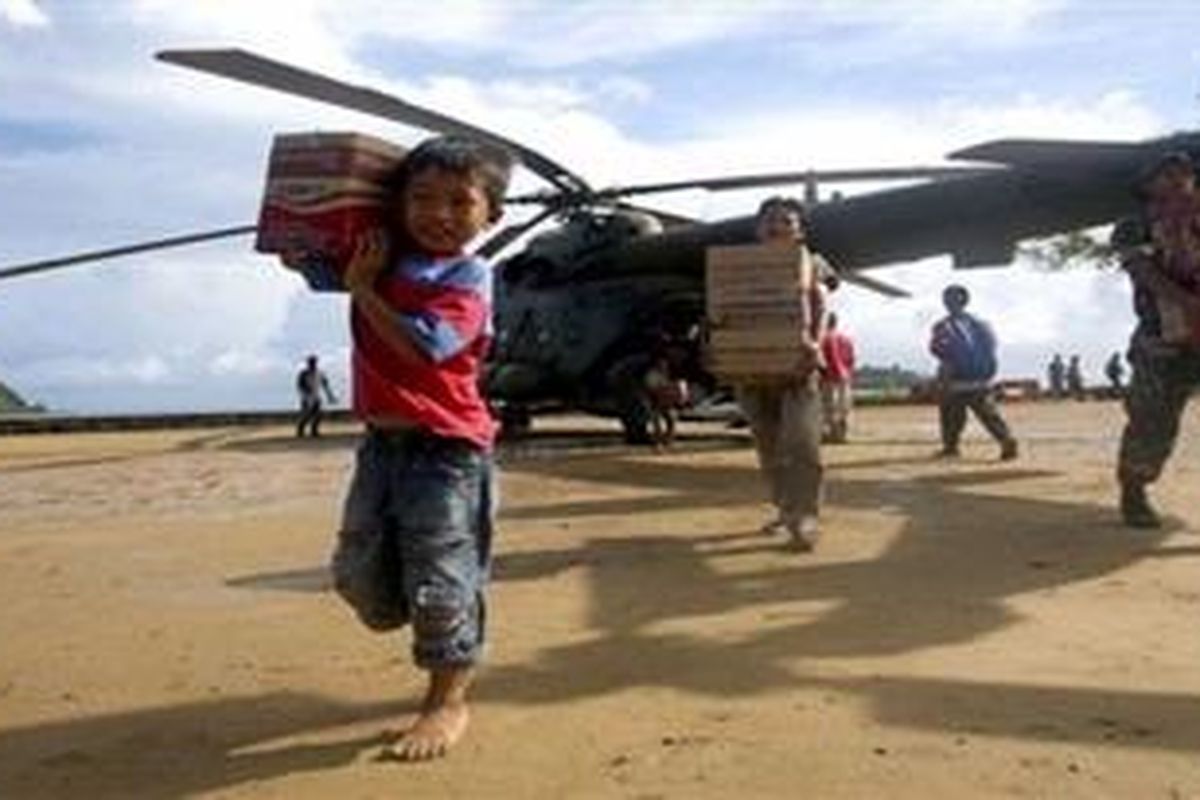 Villagers and Indonesian soldiers unload aid stuff to distribute to the tsunami victims off a military helicopter at Sikakap on Mentawai island, Indonesia, Sunday, Oct. 31, 2010. The tsunami death toll climbed to nearly 450 on Sunday with the discovery of dozens more bodies, said a National Disaster Management Agency official.