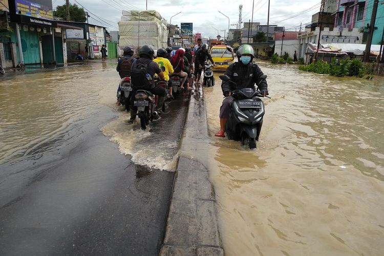 Warga melintasi banjir di Desa Lalang, Kecamatan Sunggal, Deli Serdang pada Jumat (4/12/2020).