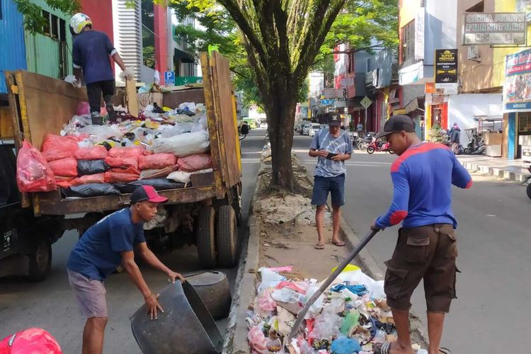 Petugas kebersihan mengangkut sampah yang menumpuk di Jalan Sam Ratulangi Kota Ambon, Rabu (18/1/2023) siang.