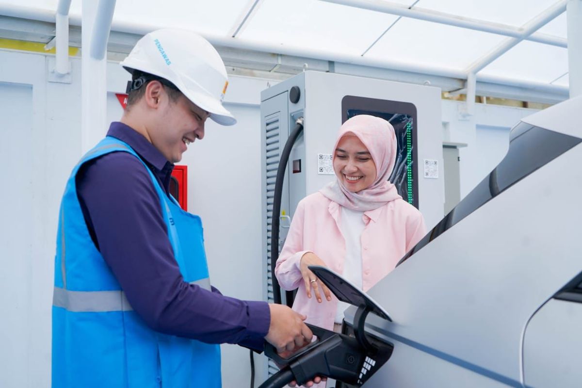 Ilustrasi pengguna electric vehicle dibantu oleh petugas PLN sedang mengisi kendaraan listriknya di SPKLU.