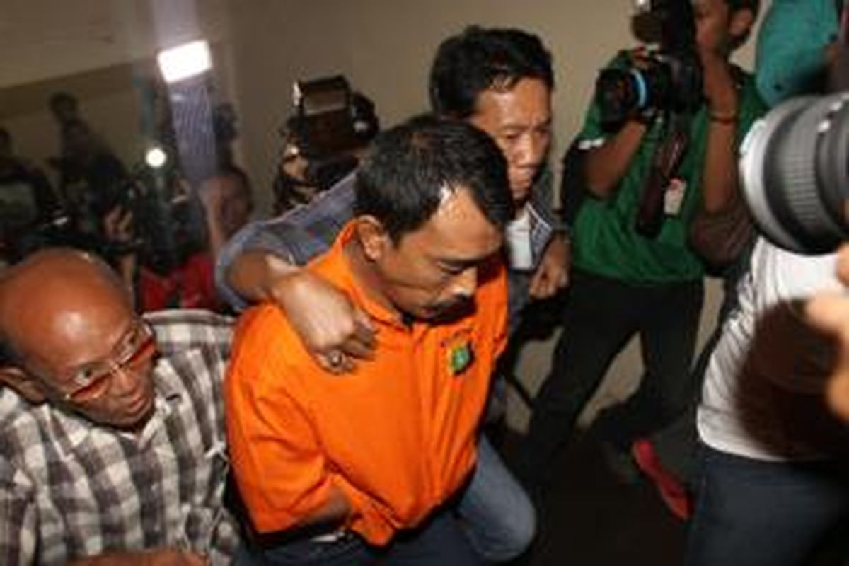 Surya Hakim digiring polisi untuk diperlihatkan saat rilis di Polda Metro Jaya, Jakarta Pusat, Rabu (16/10/2013). Polisi telah menangkap dua orang tersangka pembunuh Holly Angela Ayu, Surya Hakim dan Abdul Latif, sedangkan satu pelaku tewas sedangkan dua lagi masih buron. Polisi juga memeriksa suami Holly yang juga auditor BPK,Gatot Supiartono. 