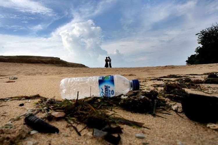 Dua wisatawan lokal mengunjungi di pantai dengan sampah rumput laut dan botol plastik di Nusa Dua, Bali, 4 Desember 2007.