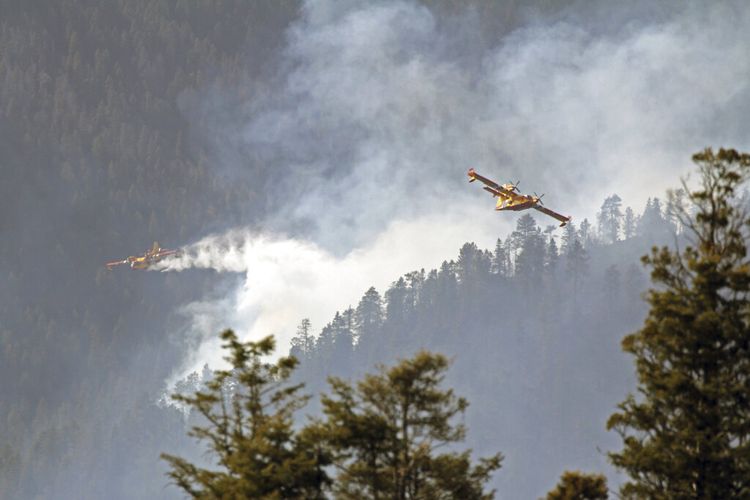 Dalam foto yang dirilis oleh U.S. Forest Service, pesawat yang dikenal sebagai super scooper memerangi Kebakaran Hermits Peak dan Calf Canyon di Hutan Nasional Santa Fe di New Mexico pada hari Selasa, 26 April 2022. 