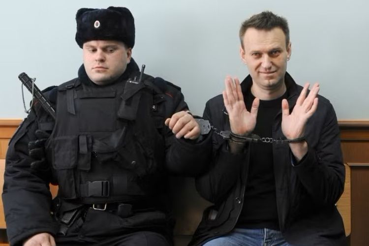 Pemimpin oposisi Rusia Alexei Navalny (kanan), berpose di depan pers saat ia duduk dengan tangan diborgol di pengadilan di Moskwa, Rusia, pada 30 Maret 2017.