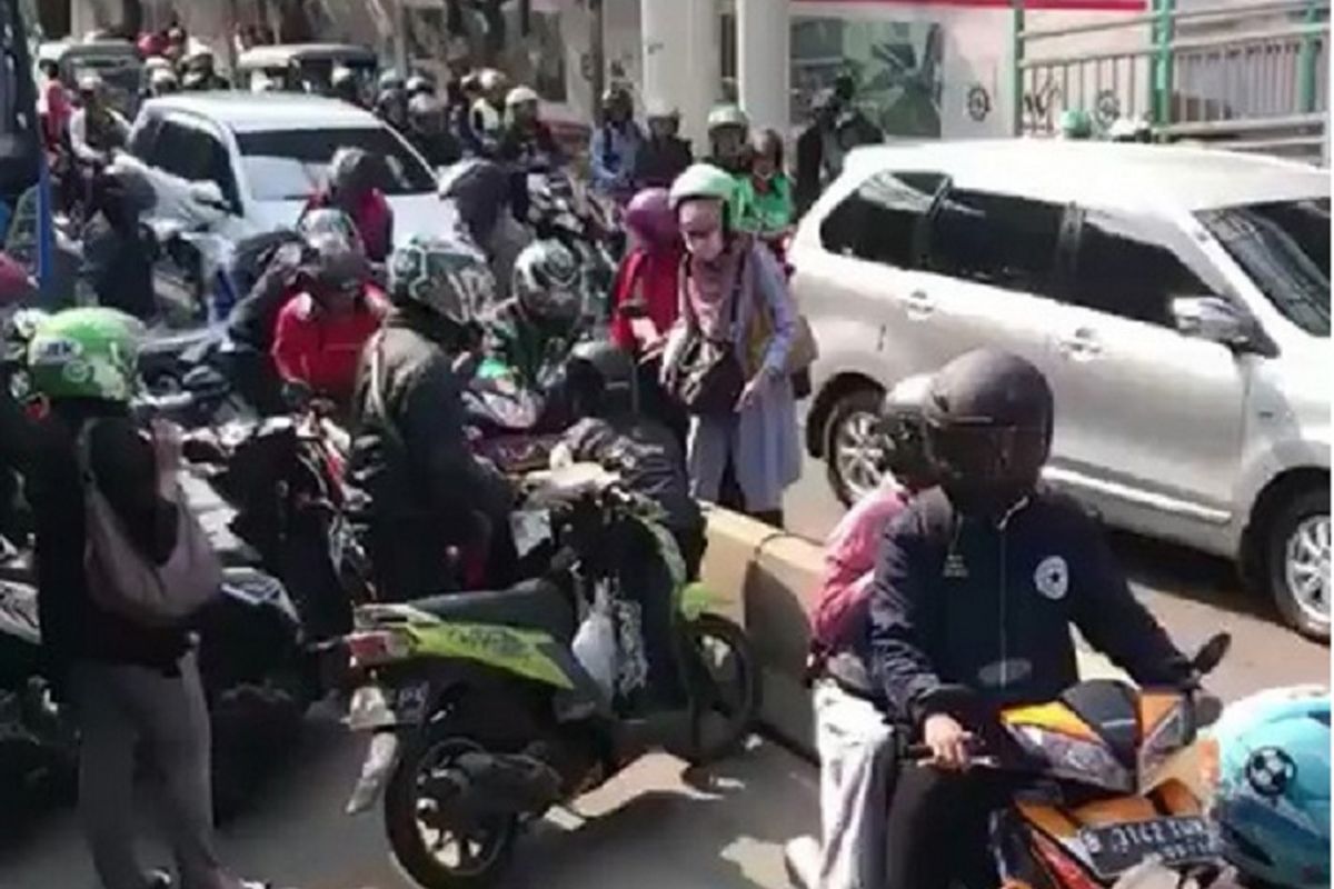 Sejumlah pengendara motor saling membantu mengangkat motor keluar dari separator jalur transjakarta.