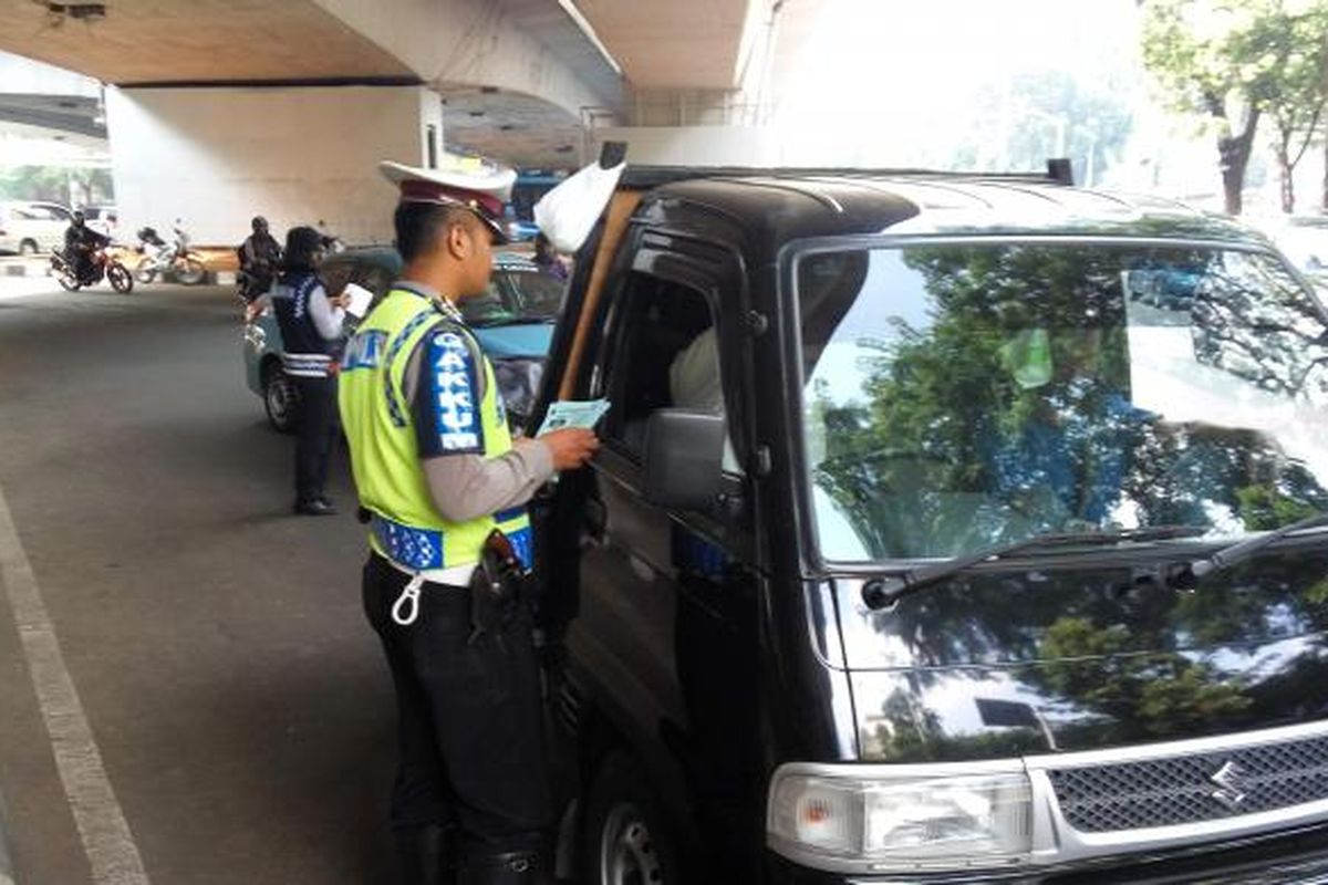 Salah satu kendaraan berpelat genap saat diberhentikan oleh petugas kepolisian karena melanggar aturan ganjil genap di kolong Fly Over Kuningan pada Jumat (5/8/2016).