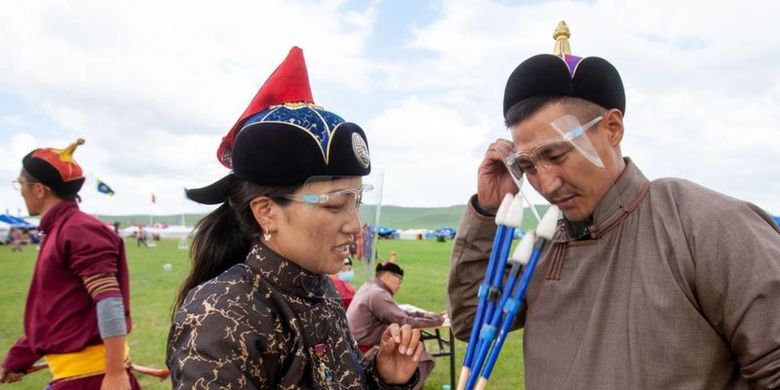 Dua warga di Mongolia tengah membahas mengenai anak panah sembari mempertahankan protokol melawan Covid-19 dengan mengenakan pelindung wajah (face shield).