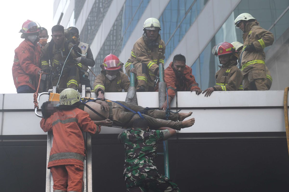 Petugas mengevakuasi korban kebakaran yang terjadi di Gedung Cyber I, Mampang, Jakarta, Kamis (2/12/2021). Dinas Penanggulangan Kebakaran dan Penyelamatan Jakarta mengerahkan 100 personel beserta 22 unit mobil pemadam ke lokasi. Api berhasil dipadamkan dalam waktu 30 menit.