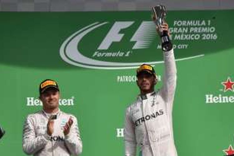 Pebalap Mercedes AMG Petronas F1 Team asal Inggris, Lewis Hamilton (kanan), mengangkat trofi yang didapat setelah memenangi balapan GP Meksiko di Autodromo Hermanos Rodriguez, Minggu (30/10/2016). Dia finis di depan rekan satu timnya asal Jerman, Nico Rosberg (kiri).