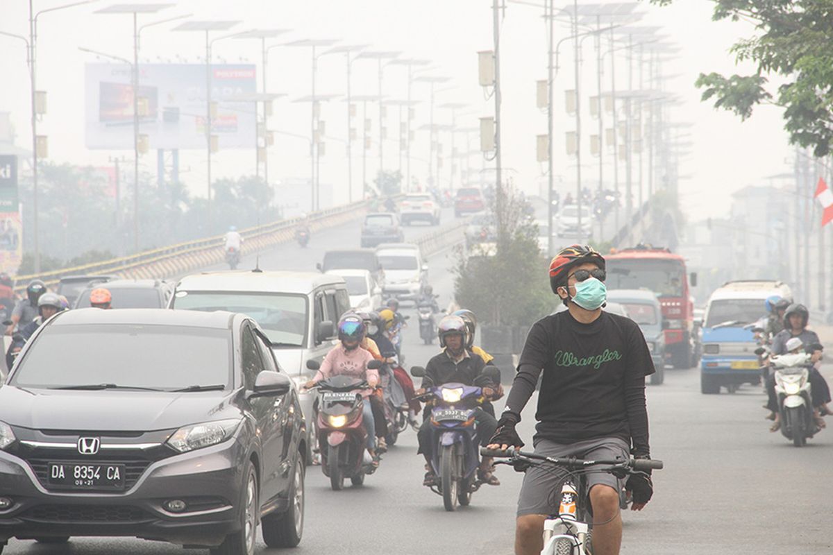 Warga bersepeda menggunakan masker pelindung pernapasan ketika melintas di Jalan Ahmad Yani yang terpapar kabut asap di Banjarmasin, Kalimantan Selatan, Minggu (15/9/2019). Kebakaran hutan dan lahan (Karhutla) di sejumlah wilayah Provinsi Kalsel mengakibatkan Kota Banjarmasin terpapar kabut asap dengan aroma yang menyengat dan bertambah pekat dalam beberapa hari terakhir.