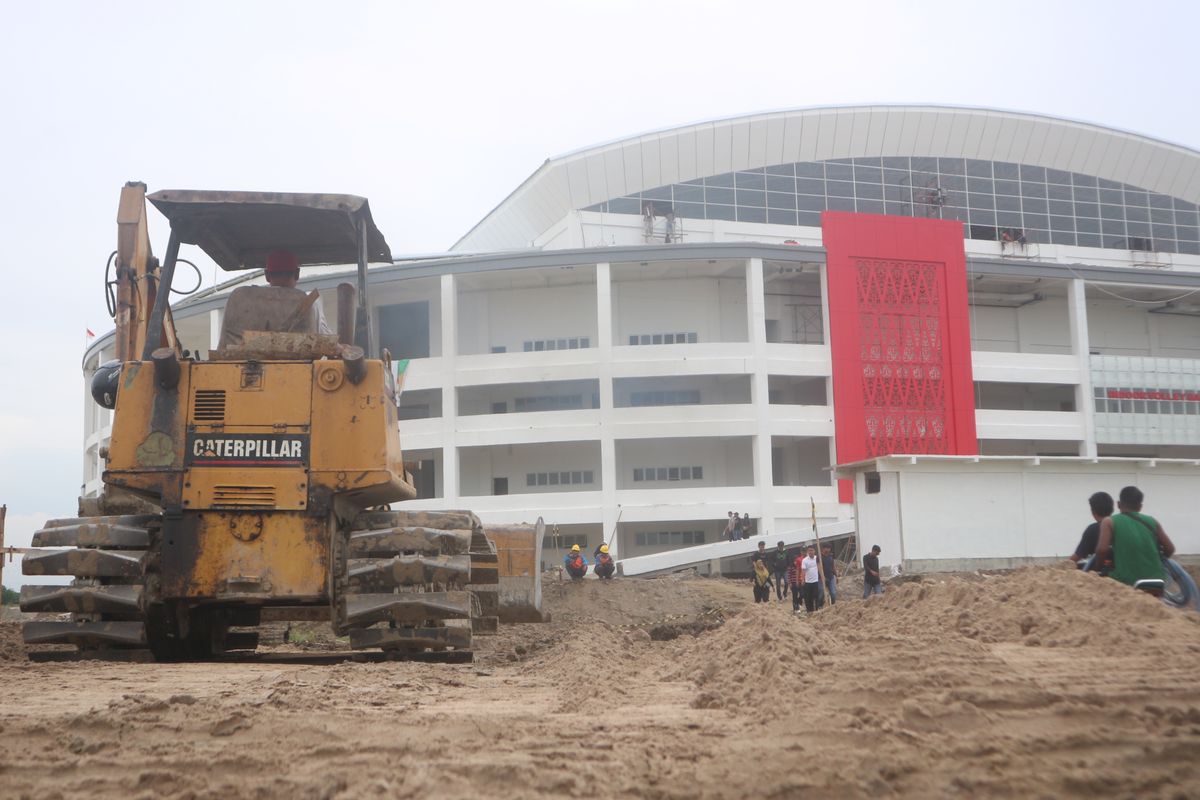 Alat berat meratakan tanah timbun di akses jalan berkubang menuju venue voli Indoor di Sport Center Sumut, di Desa Sena, Deli Serdang, Selasa (10/9/2024)