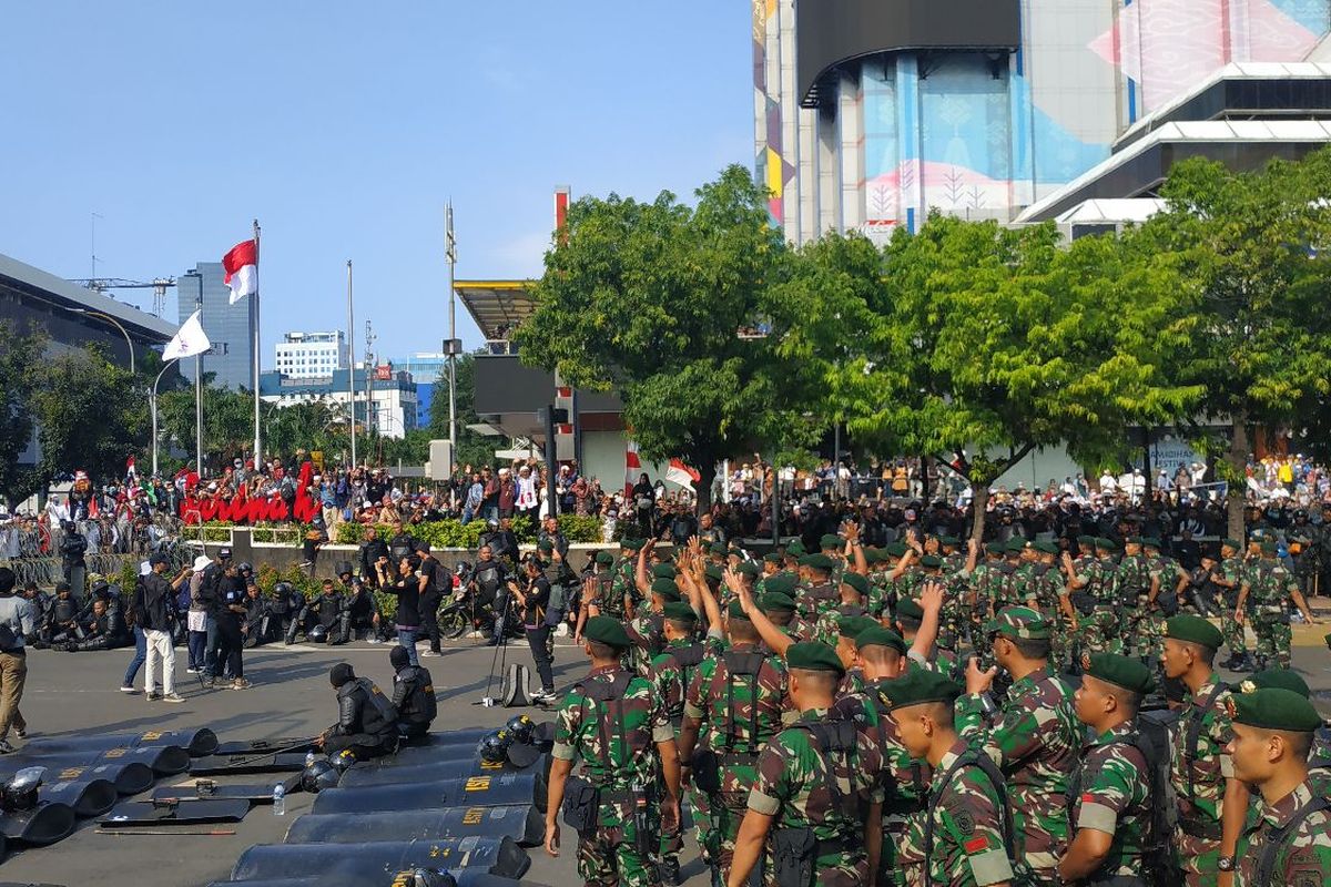Pasukan Kostrad melambaikan tangan ke arah massa yang berunjuk rasa di depan Kantor Bawaslu di Jalan MH Thamrin di Jakarta Pusat, Rabu (22/5/2019).