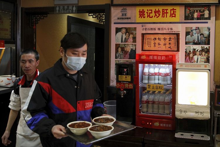 Seorang pria membawa makanannya di depan foto lalu Joe Biden yang dipajang di sebuah restoran mi di China pada Minggu (8/11/2020). Biden sempat mengunjungi restoran bernama Yaoji Chaogan ketika berkunjung di China pada 2011 ketika masih menjabat sebagai Wakil Presiden AS. Para pemimpin dunia memberi Biden ucapan selamat atas kemenangannya dalam pilpres AS 2020.