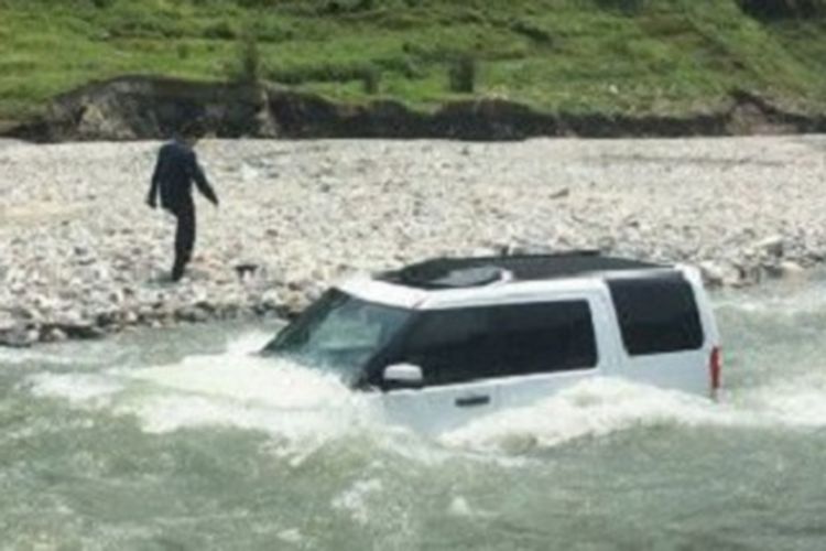 Seorang pria menunggu di tepi sungai seraya melihat mobilnya tergenang. Dia membawa mobil Land Rover-nya ke sungai untuk dibersihkan daripada menghamburkan uang ke tempat cuci mobil.