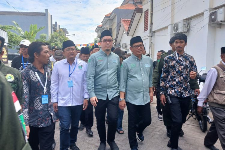 Pasangan calon (paslon) Abdul Ghofur-Firosya Shalati, memilih berjalan kaki saat mendaftar ke kantor KPU Lamongan, Jawa Timur, Rabu (28/8/2024).