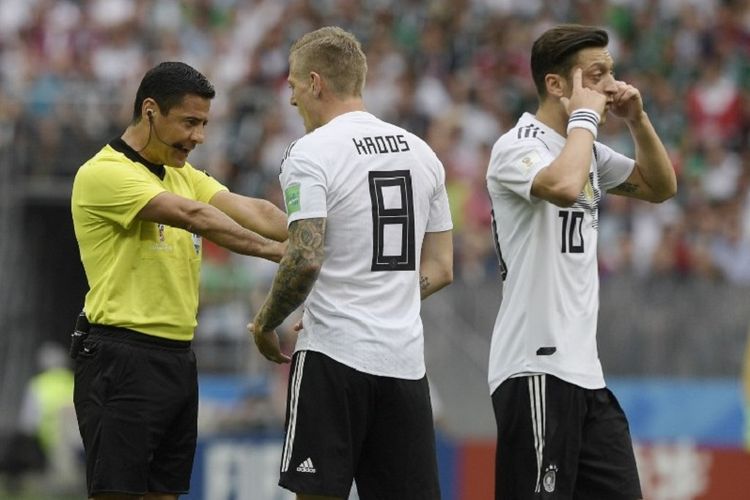 Wasit Alireza Faghani berbicara dengan Toni Kroos dan Mesut Oezil pada pertandingan Jerman vs Meksiko di Stadion Luzhniki, 17 Juni 2018. Wasit asal Iran itu pernah 6 kali memimpin partai Liga 1. 