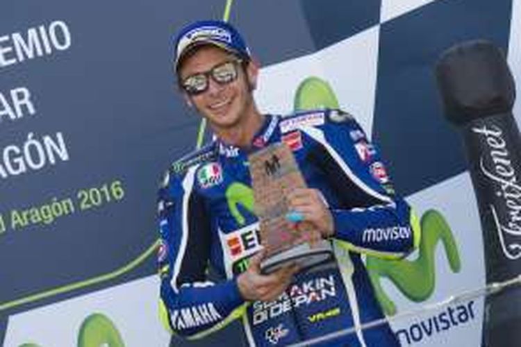 Pebalap Movistar Yamaha asal Italia, Valentino Rossi, berpose dengan trofi yang didapat setelah finis di urutan keempat pada balapan GP Aragon di Sirkuit MotorLand Aragon, Minggu (25/9/2016).