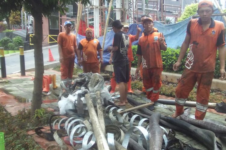 Petugas PPSU Kelurahan Kuningan Barat atau pasukan oranye saat menemukan kulit kabel dari dalam gorong-gorong Jalan Gatot, Jakarta Selatan. 