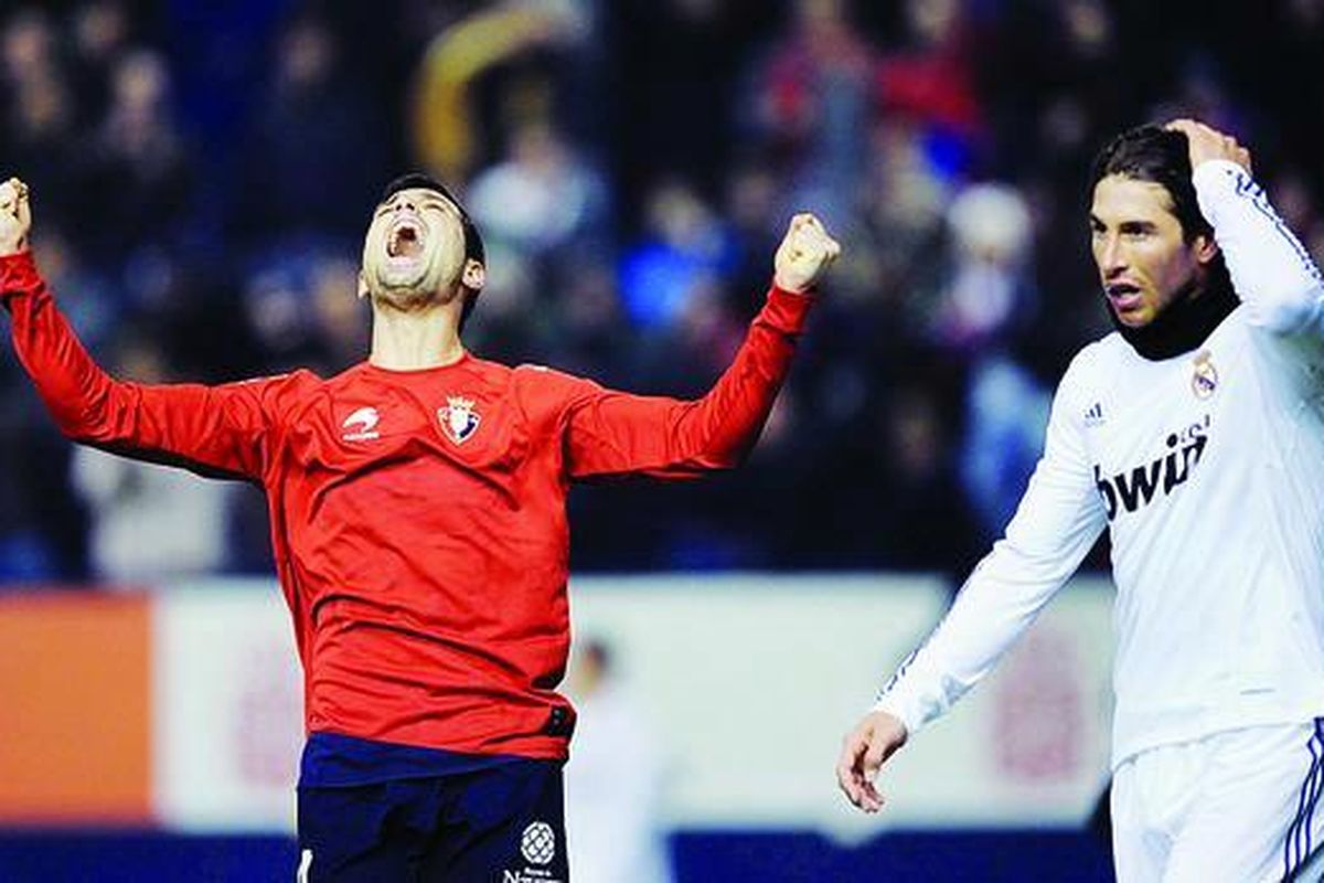 Pemain Osasuna, Miguel Flano (kiri), meluapkan kegembiraan, sementara pemain Real Madrid, Sergio Ramos, meninggalkan lapangan dengan wajah lesu usai laga Liga Spanyol yang dimenangi Osasuna 1-0 di Stadion Reyno de Navarra, Pamplona, Spanyol, Minggu (30/1).