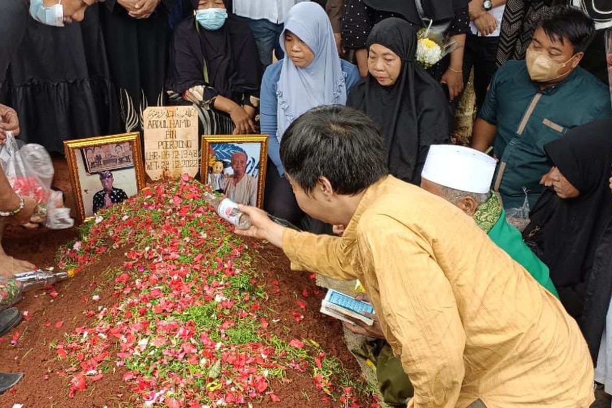 Anggota keluarga dari almarhum Abdul Hamid alias Pak Ogah, saat menaburkan bunga, dan menyiram pusara almarhum dengan air mawar di TPU Jatirasa, Jatiasih, Kota Bekasi pada Kamis (29/12/2022). Abdul Hamid dikebumikan di TPU Jatisari tepat setelah adzan dzuhur berkumandang.