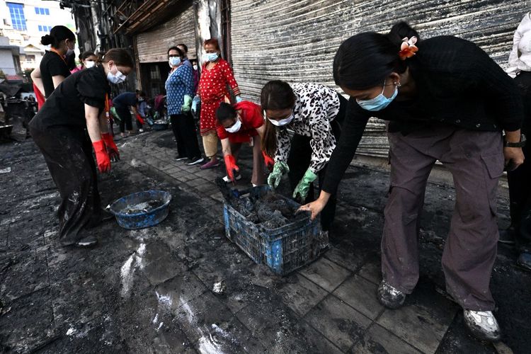 Warga setempat membersihkan puing-puing supermarket yang terbakar setelah dibakar dalam aksi protes di Kathmandu pada 13 September 2025. Ibu kota Nepal pada 13 September kembali normal setelah protes antikorupsi yang mematikan.